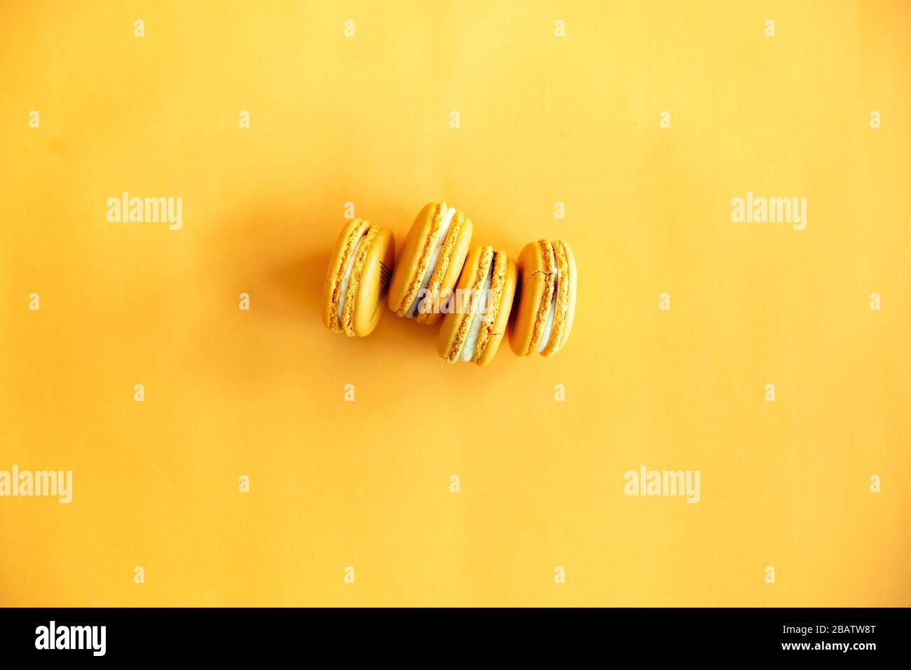 Draufsicht auf schmackhafte orangegelbe Makronen. Konzepte Ideen Hintergrund auf gelbem Papier, Planlay und Kopierraum Stockfoto