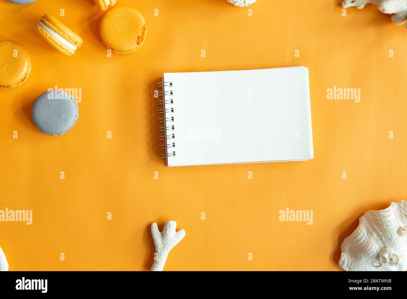 Draufsicht über schmackhafte orangegelbe Makronen und leere Note. Konzepte Ideen Hintergrund auf gelbem Papier, Planlay und Kopierraum. Verwenden der Vorlage für Mock-up Stockfoto