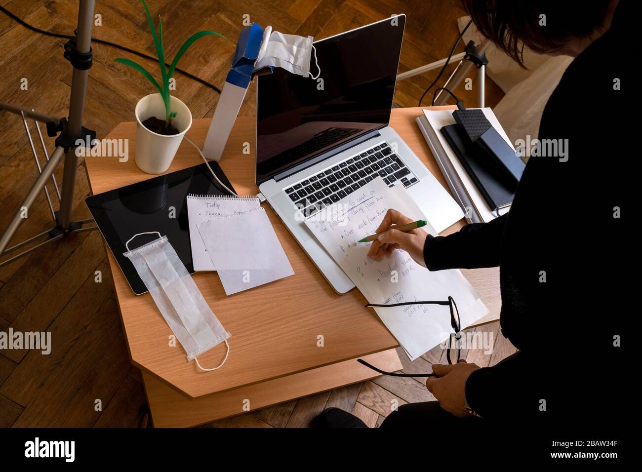 Frau arbeitet zu Hause. Die medizinische Maske ist auf dem Laptop. Nahaufnahme des Arbeitsplatzes während der Pandemie. Das Konzept, zu Hause zu bleiben. Stockfoto