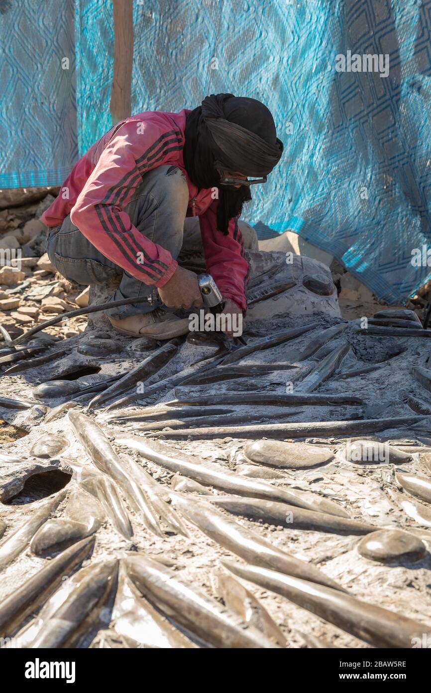 Ein Arbeiter, der Ammoniak und verschachfene Fossilien in Erfoud, Marokko, säubert Stockfoto