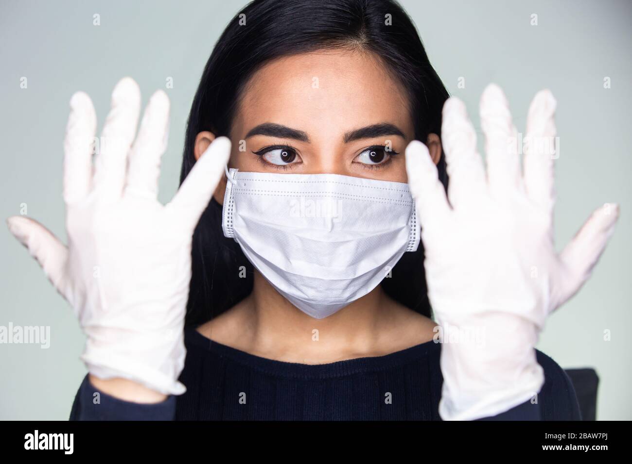 Coronavirus-Ausbruch: Eine asiatische Frau, die medizinische Gummihandschuhe und eine Einwegmaske ansetzt, um ansteckende Viren zu vermeiden. Stockfoto