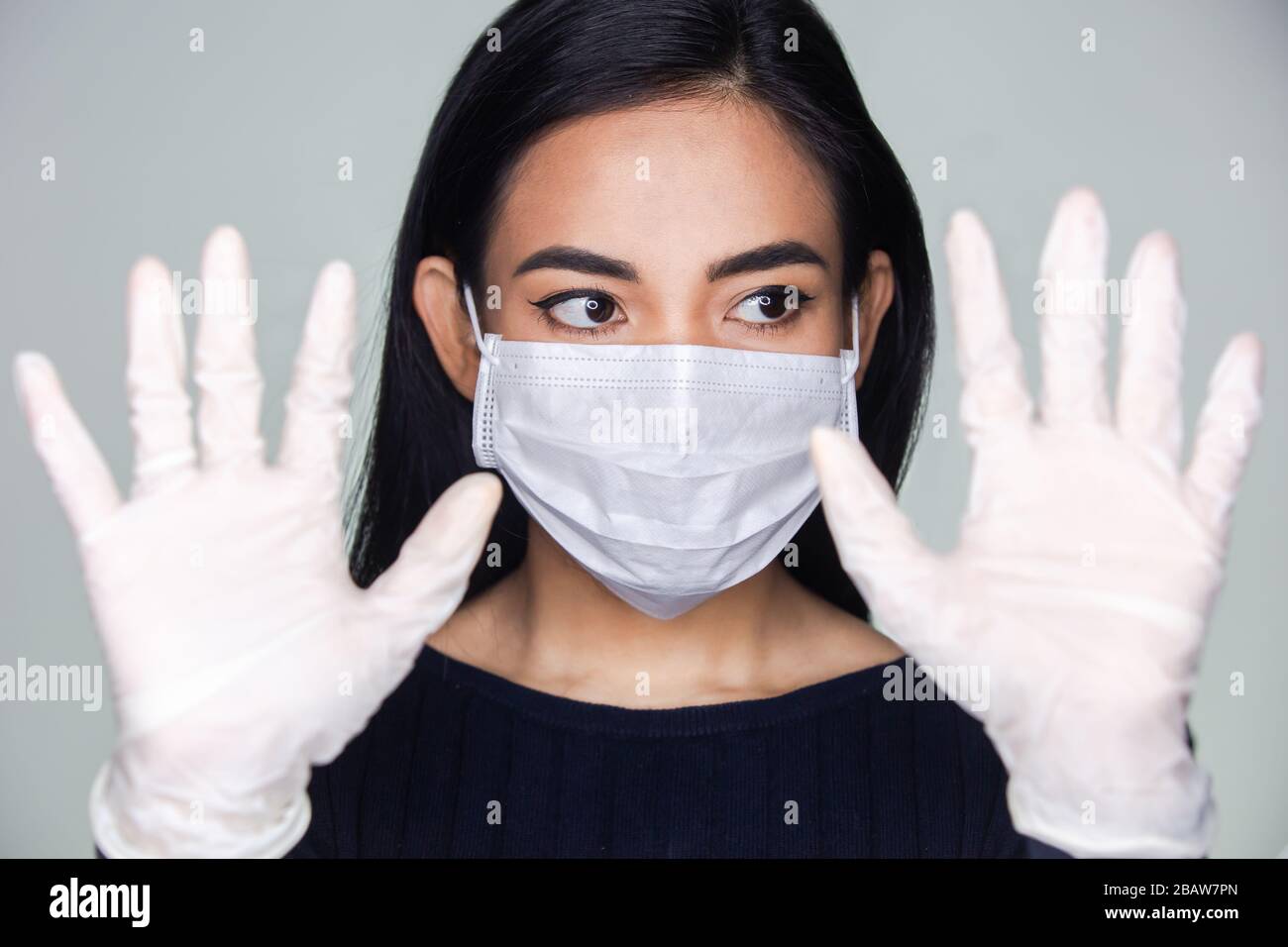 Coronavirus-Ausbruch: Eine asiatische Frau, die medizinische Gummihandschuhe und eine Einwegmaske ansetzt, um ansteckende Viren zu vermeiden. Stockfoto