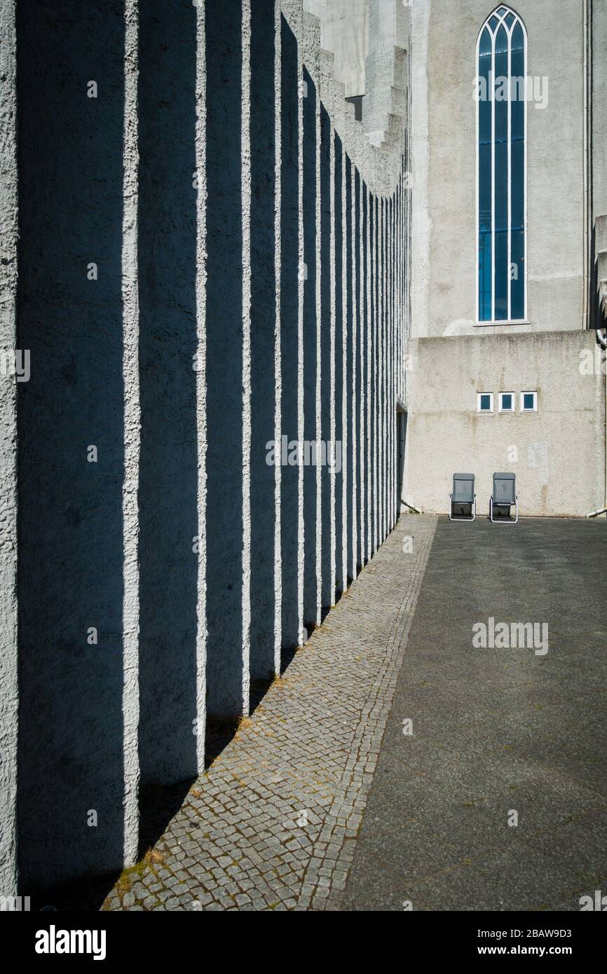 Großartige architektonische Nahaufnahme der Hallgrimskirkja-Flügel und Klappstühle unter dem Kirchenfenster. Sonniger Tageslichtschuss, keine Menschen sichtbar. Stockfoto