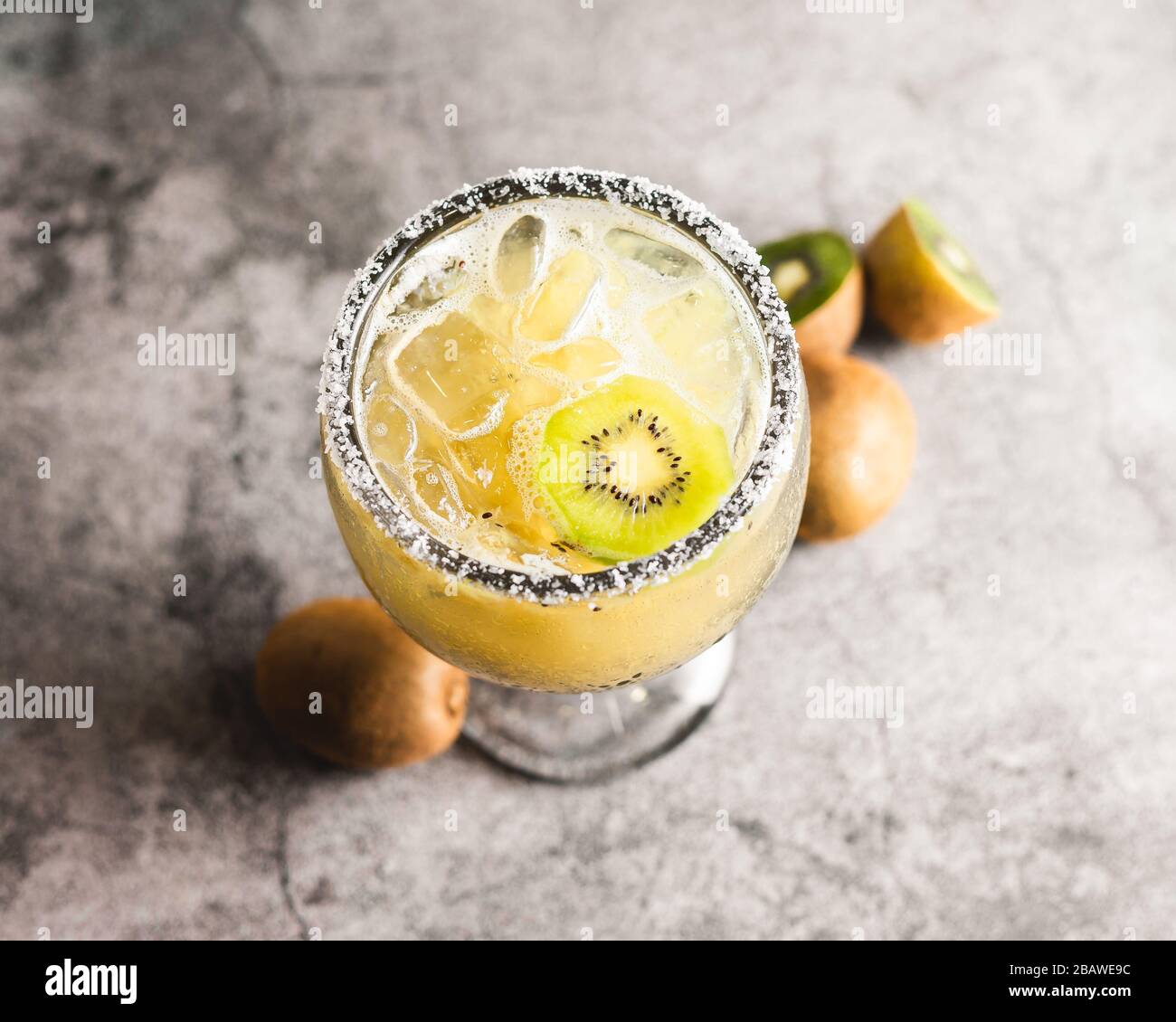 Kiwi margarita hoher Winkel in großem margarita-glas mit Salz auf dem Rand Eis geschnitten Kiwi whol kiwi graue Oberfläche Stockfoto