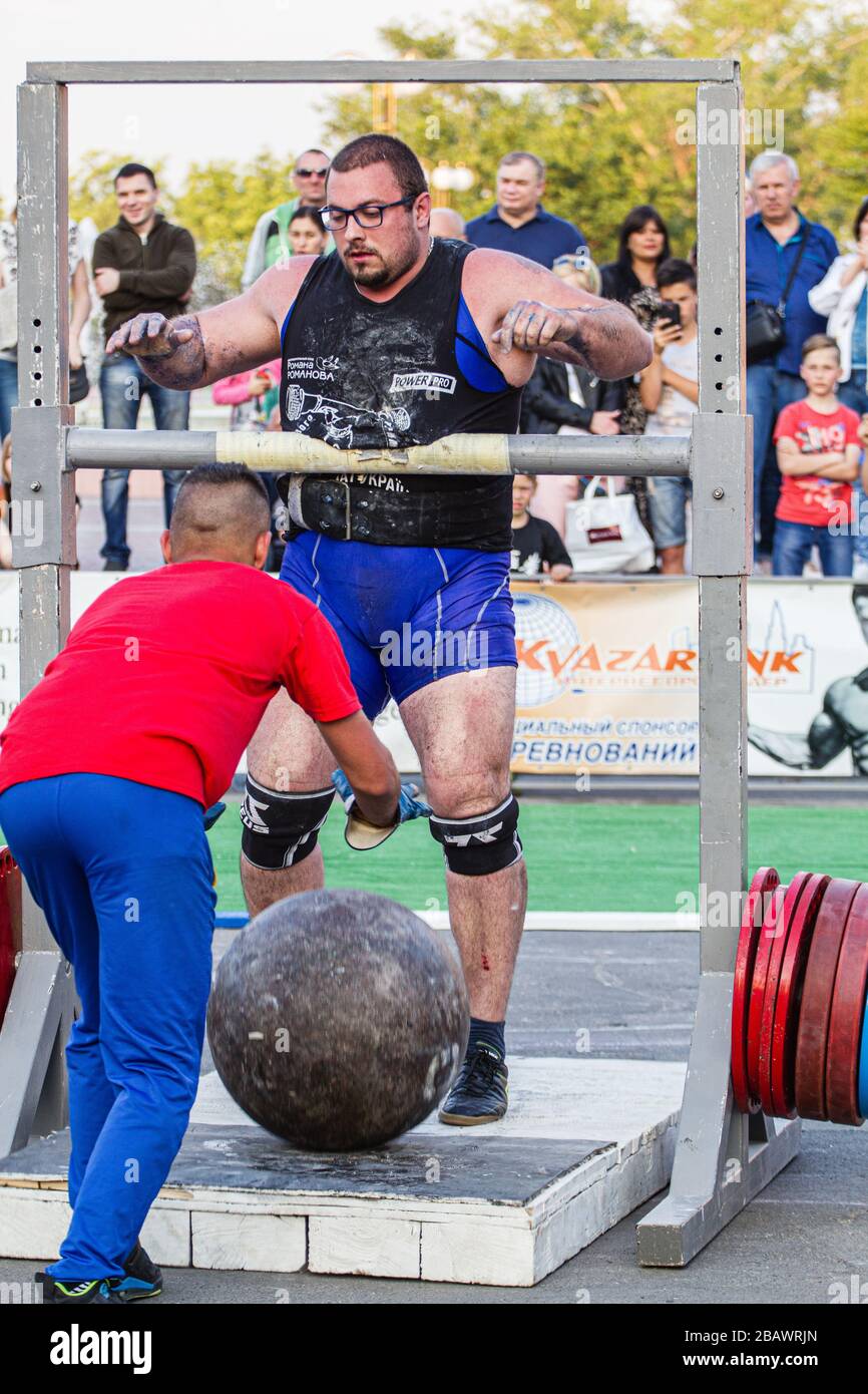Melitopol, Ukraine, Datum 27. Mai 2017, Strongman wirft einen schweren Steinball durch die Querstange Stockfoto
