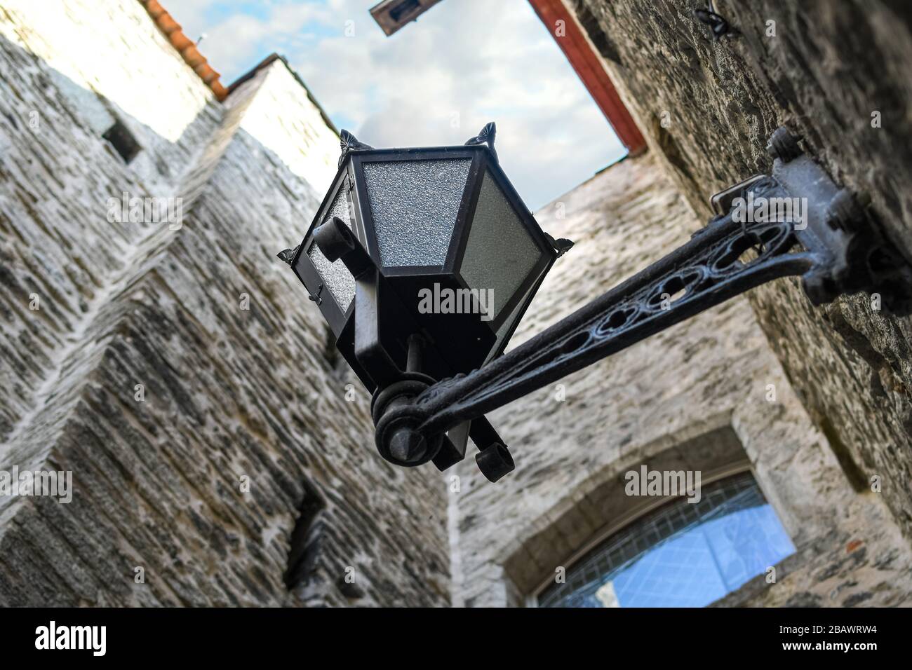Selektiver Fokusschuss einer Straßenleuchte aus dem 19. Jahrhundert, die von unten in einer schmalen mittelalterlichen Gasse in der Stadt Tallinn Estland zu sehen ist. Stockfoto