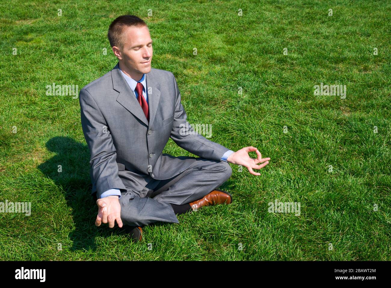 Ruhe Geschäftsmann sitzen mit geschlossenen Augen Meditation im Sitzen yoga Pose draußen in der frischen, grünen Wiese Stockfoto