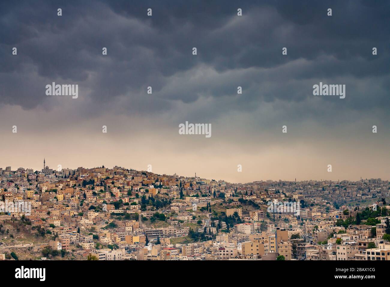 Bedrohliche Sturmwolken, die sich über dicht besiedelten Hügeln der Altstadt von Amman, Jordanien, abzeichnen. Stockfoto
