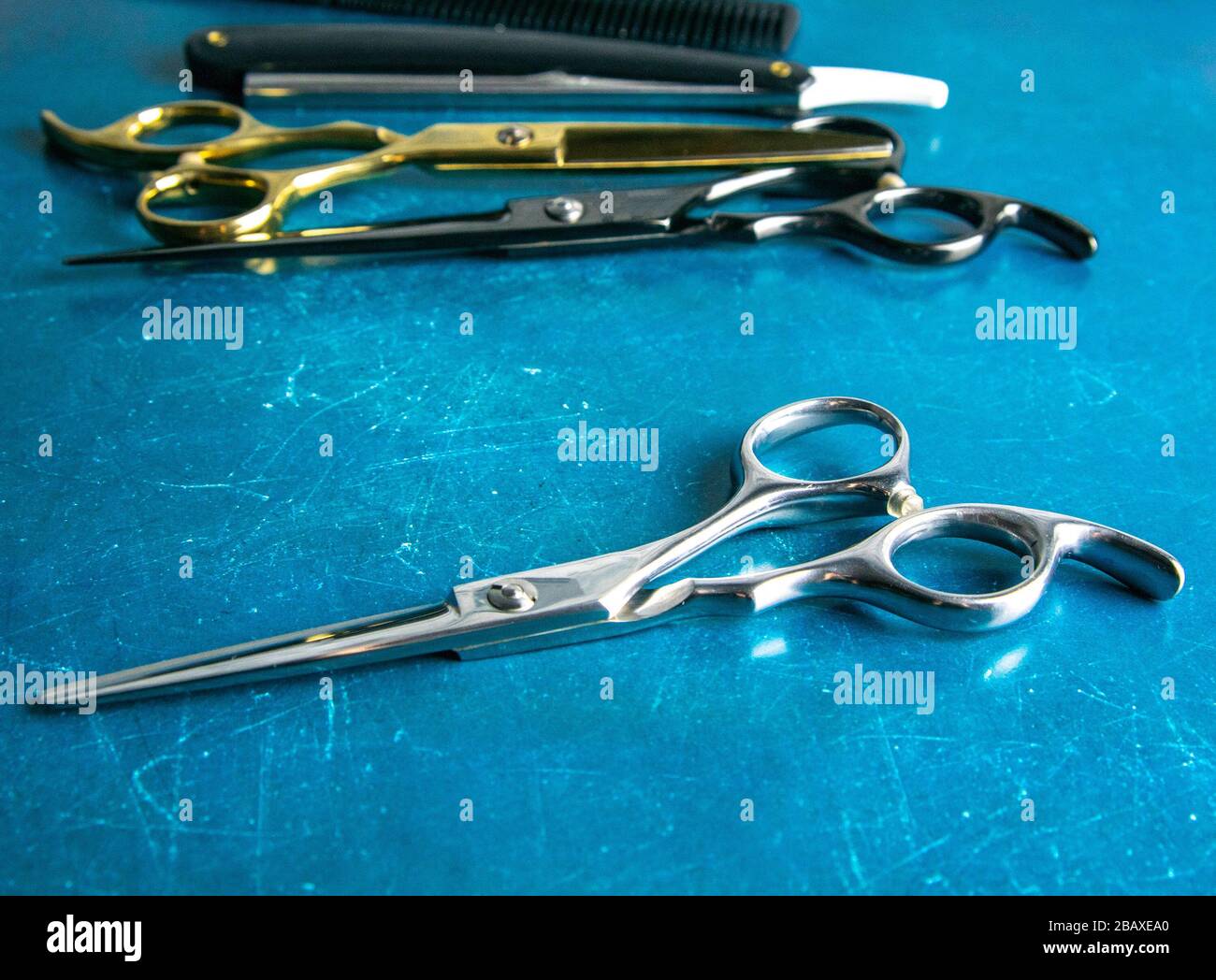 Frisierwerkzeuge, Schere, Haarschneider, Kamm, gefährlicher Rasierer,  Haargel stehen auf blauem Grund Stockfotografie - Alamy