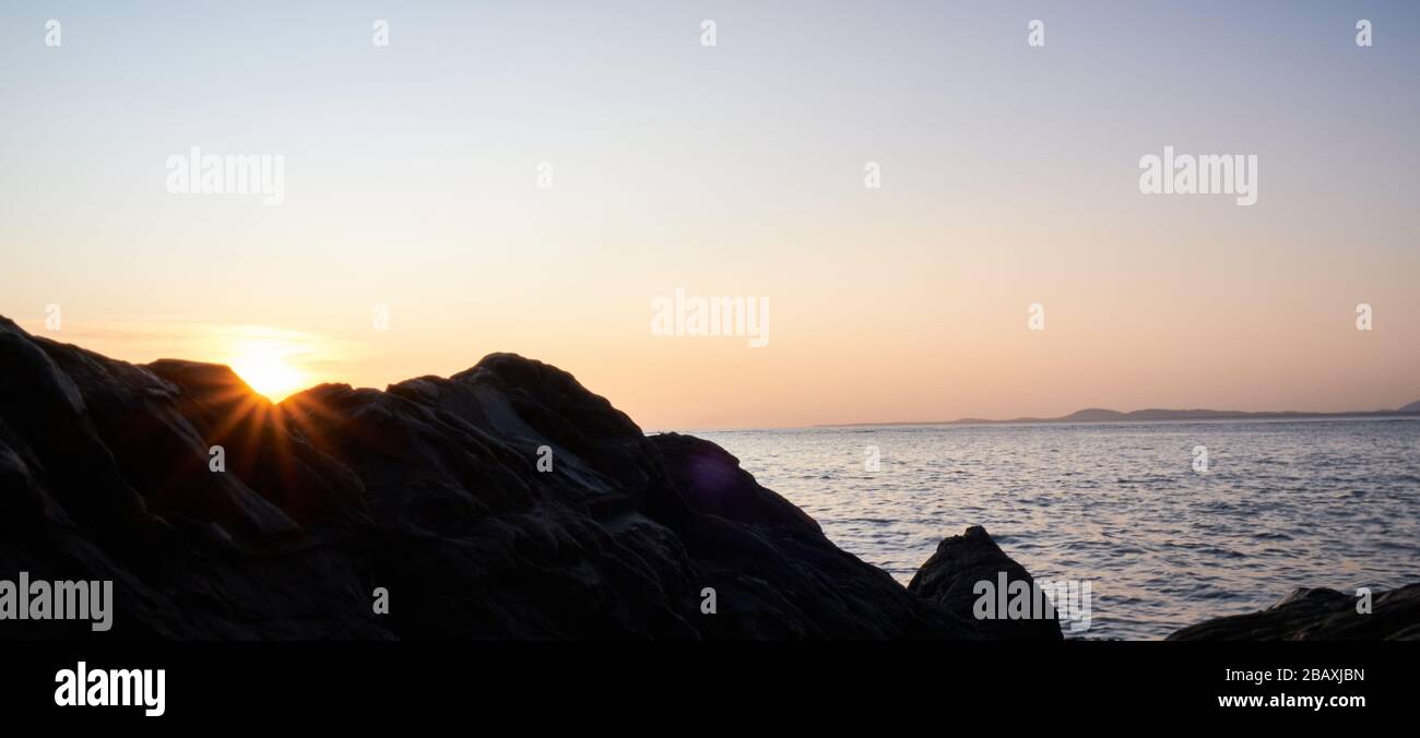Blick auf die Sonne oder die Sternensonne über den Felsen mit Sonnenuntergang am Hintergrund im atlantik, Punta Ballena, Maldonado, Uruguay Stockfoto
