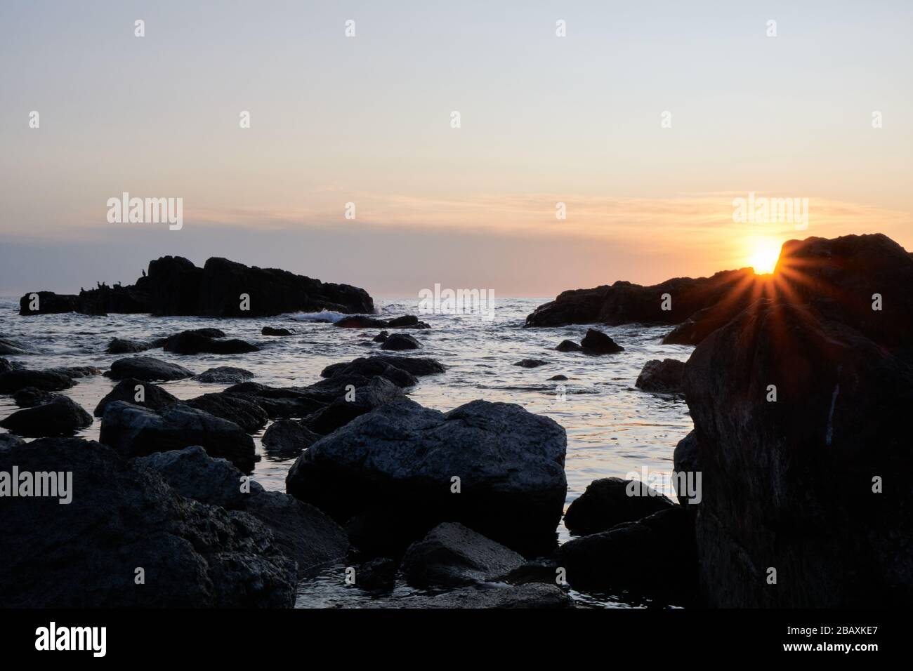 Blick auf die Sonne oder die Sternensonne über den Felsen mit Sonnenuntergang am Hintergrund im atlantik, Punta Ballena, Maldonado, Uruguay Stockfoto