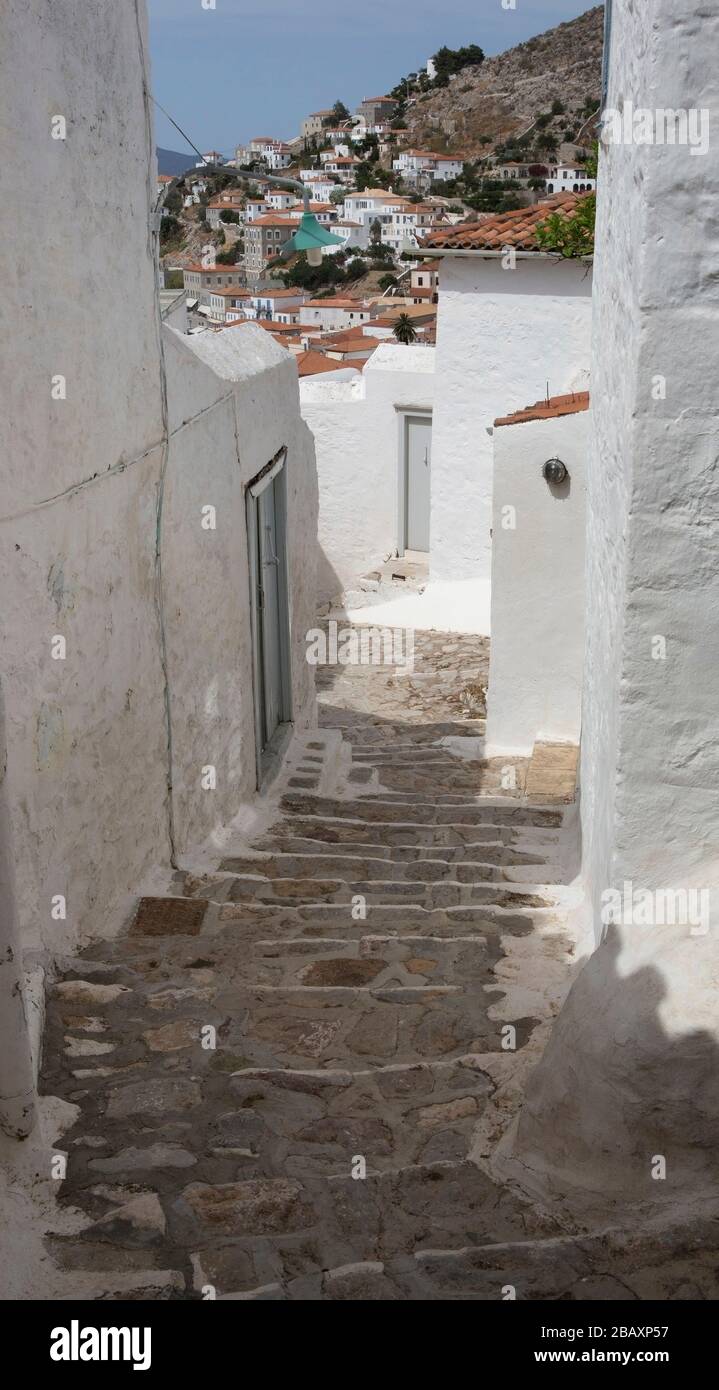 Steiler und enger Gehweg zwischen Wohnungen und Wohnhäusern auf der griechischen Insel Hydra, Griechenland. Stockfoto