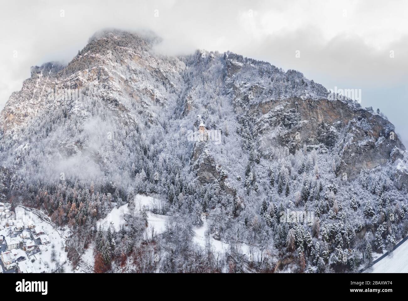 Blick auf den Berg mit Grenzturm, Wald unter Nebel, in der Schweiz schneebedeckte Hänge, bewölkte Atmosphäre, schöne Bedingungen Stockfoto