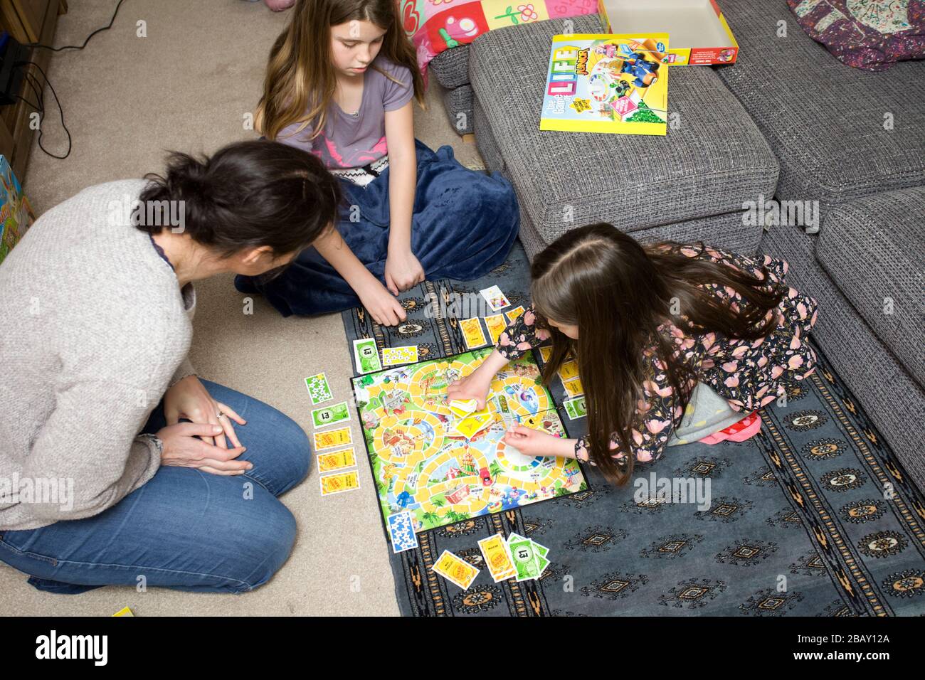 Familie spielt auf dem Wohnzimmerboden, England, ein Spiel des Lebens Stockfoto