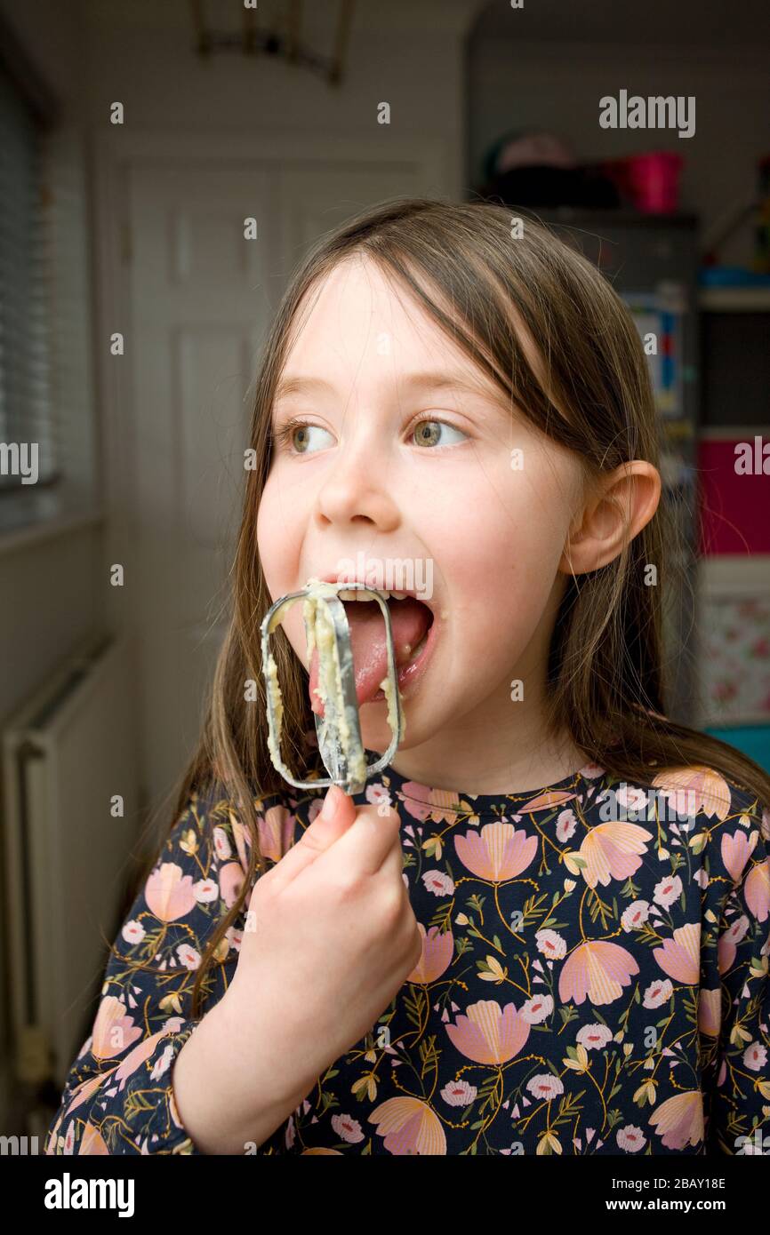 Junges Mädchen leckt den Kuchen Mix aus Mischpaddel Stockfoto