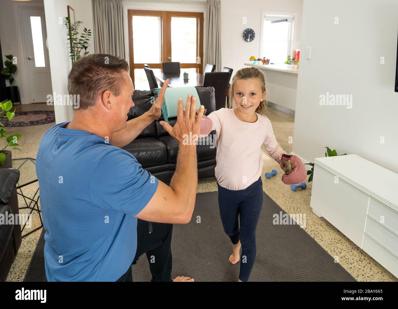 COVID-19-Abschaltung. Glücklicher Vater und Tochter boxten während der Quarantäne zusammen. Die Familie hat Spaß daran, körperliche Bewegung im Innenbereich zu machen. Bleiben Sie zu Hause, trainieren Sie Stockfoto