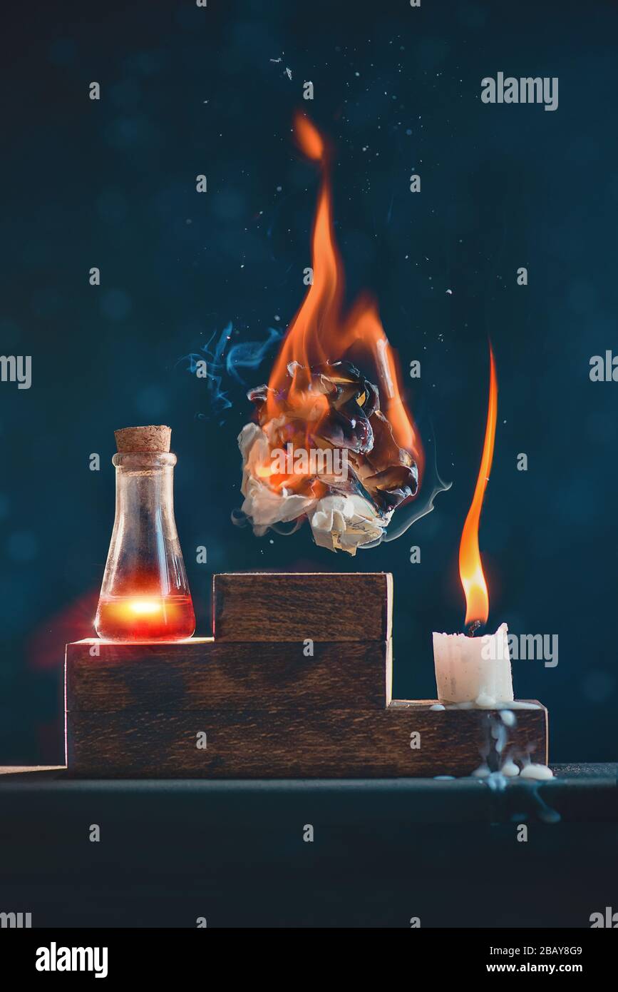 Zerknitterte Papierkugel in Brand, Kerze und Liebestränke auf einem Siegerpodest Stockfoto