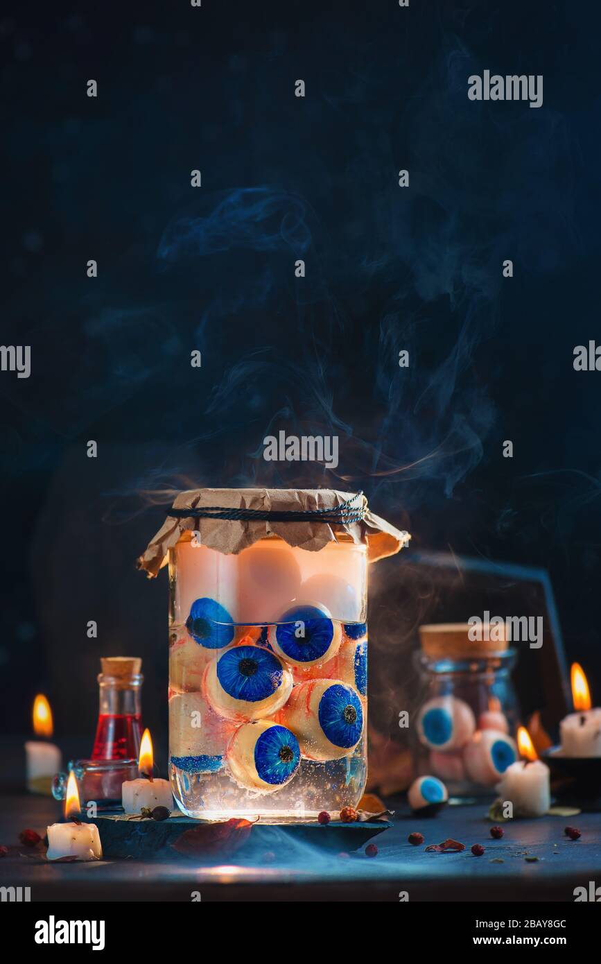 Glaskanne mit Augäpfeln, gruseliges Halloween-Konzept mit Kerzen Stockfoto