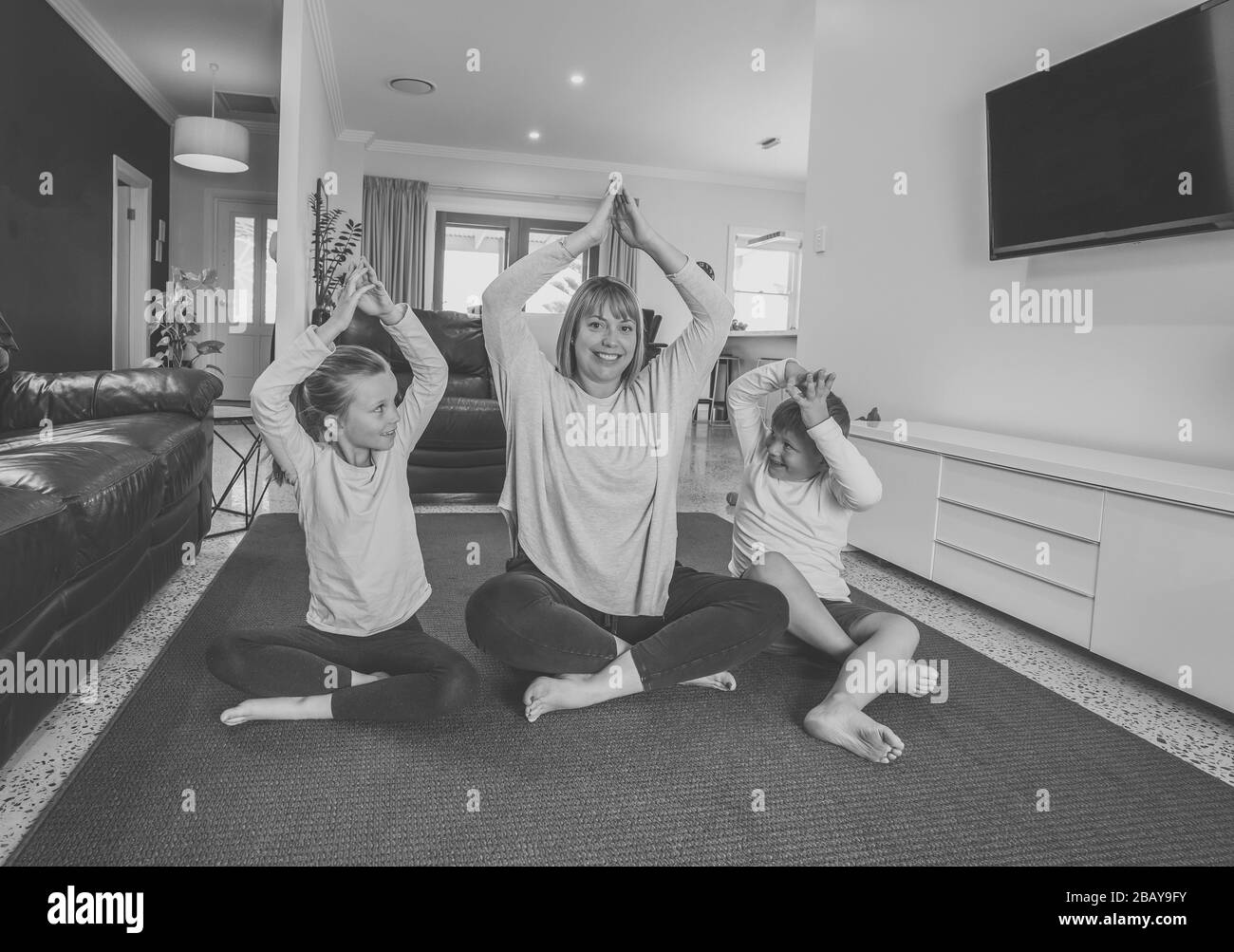 COVID-19-Abschaltung. Kaukasische Familie, die zu Hause Yoga in Quarantäne macht. Mutter, Tochter und Sohn, die während des Lockdowns meditieren. Gesundheit, Trainingsaufenthalt Stockfoto
