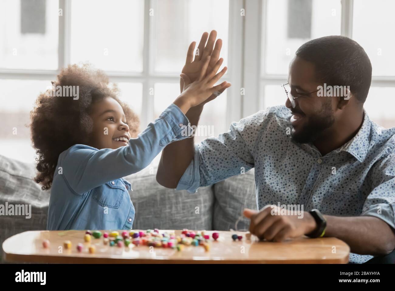 Die afrikanische Tochter gibt dem Vater, der mit der Zeitvertreibstätigkeit beginnt, hohe fünf Stockfoto