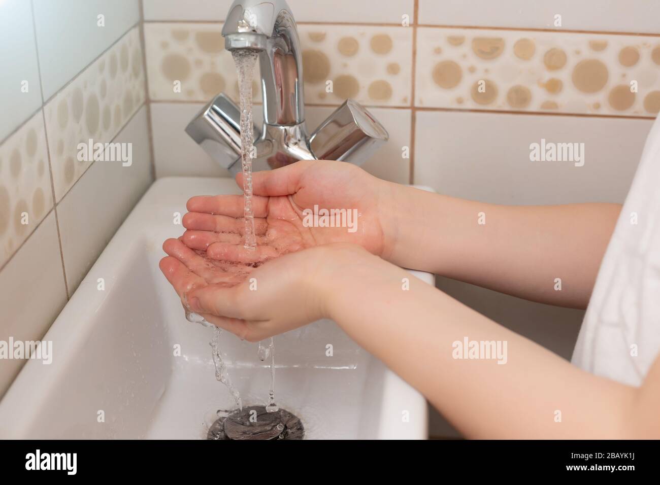 Die Hände der Kinder über dem Waschbecken im Badezimmer mit strömendem Wasser. Nahaufnahme Stockfoto