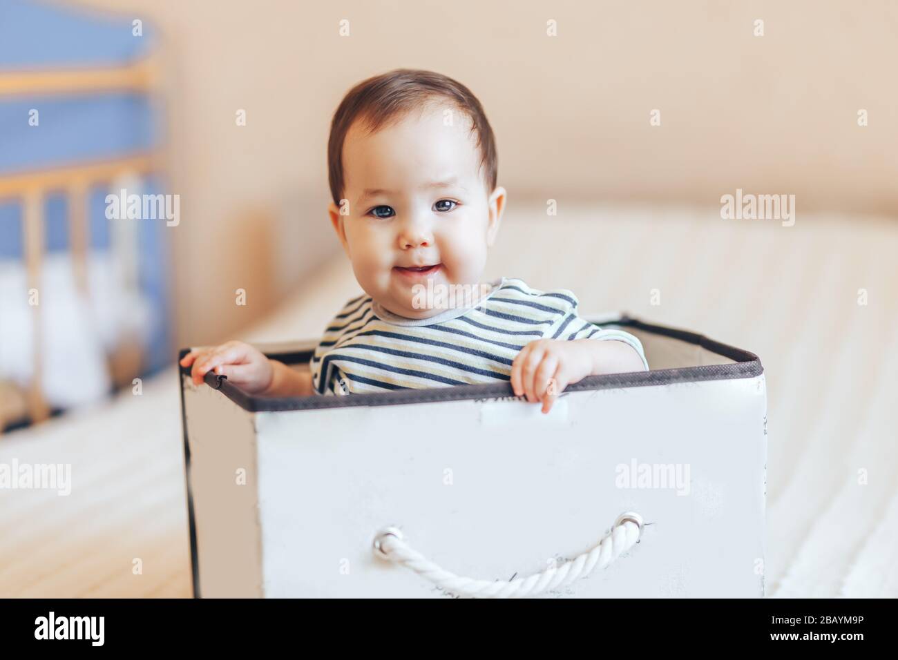 Hübsches Baby Kleinkind Junge oder Mädchen, das in einer Kiste in der Wohnung sitzt Stockfoto