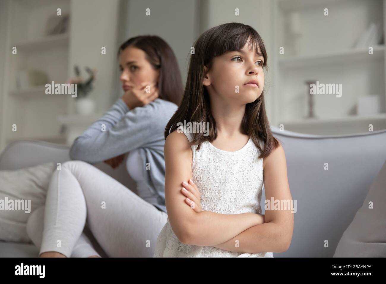Junge Mutter und kleine Tochter vermeiden es, nach Familienmissverständnissen zu sprechen Stockfoto