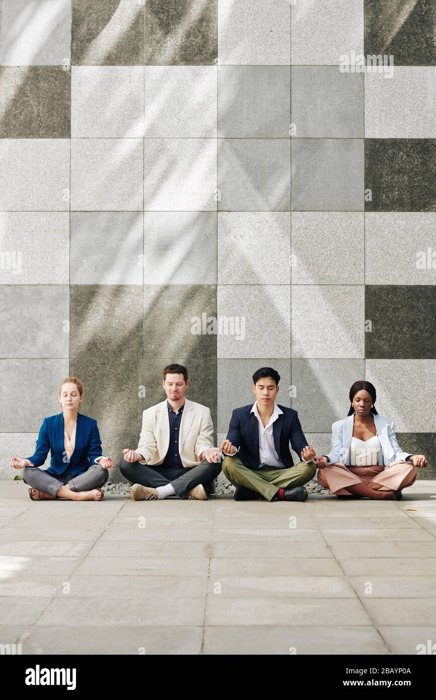 Erfolgreiches multiethnisches Business-Team, das gemeinsam die Meditation praktiziert Stockfoto