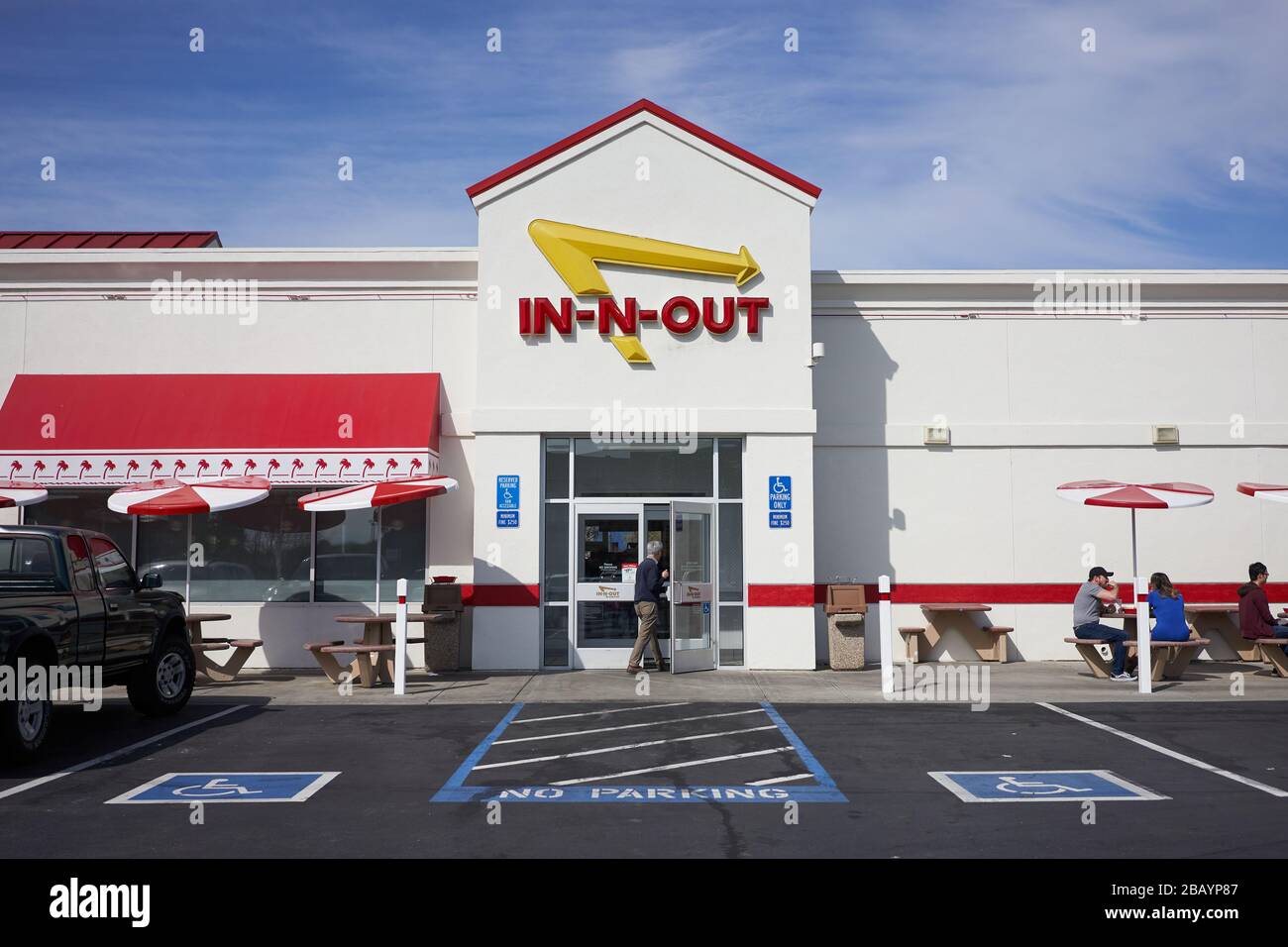 Ein Mann betritt ein Redwood City-Lokal in der Fast-Food-Restaurantkette in-N-Out. Ein paar Restaurantbesucher wählen Outdoor-Sitzplätze. Stockfoto