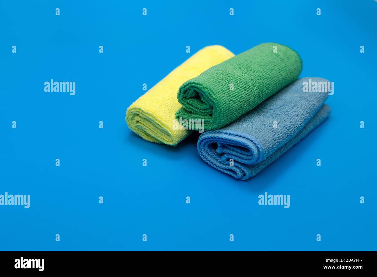 Bunte, trockene Mikrofasertücher zur Reinigung verschiedener Oberflächen in Küche, Bad und anderen Zimmern, auf blauem Hintergrund. Leere Stelle für Text oder Logo Stockfoto