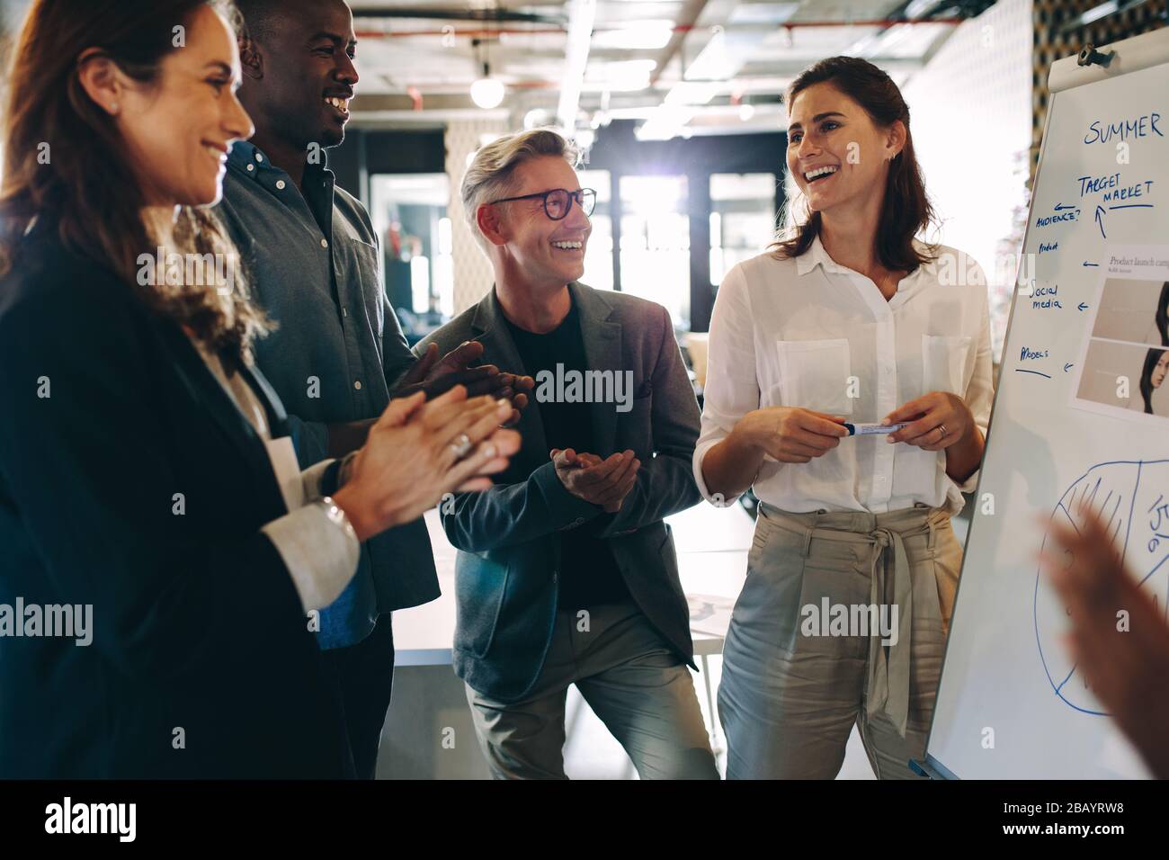 Gruppe von Geschäftsleuten, die die Präsentation vor Teamkollegen im Büro schätzen. Das Business Team klatscht nach einer erfolgreichen Präsentation die Hände. Stockfoto