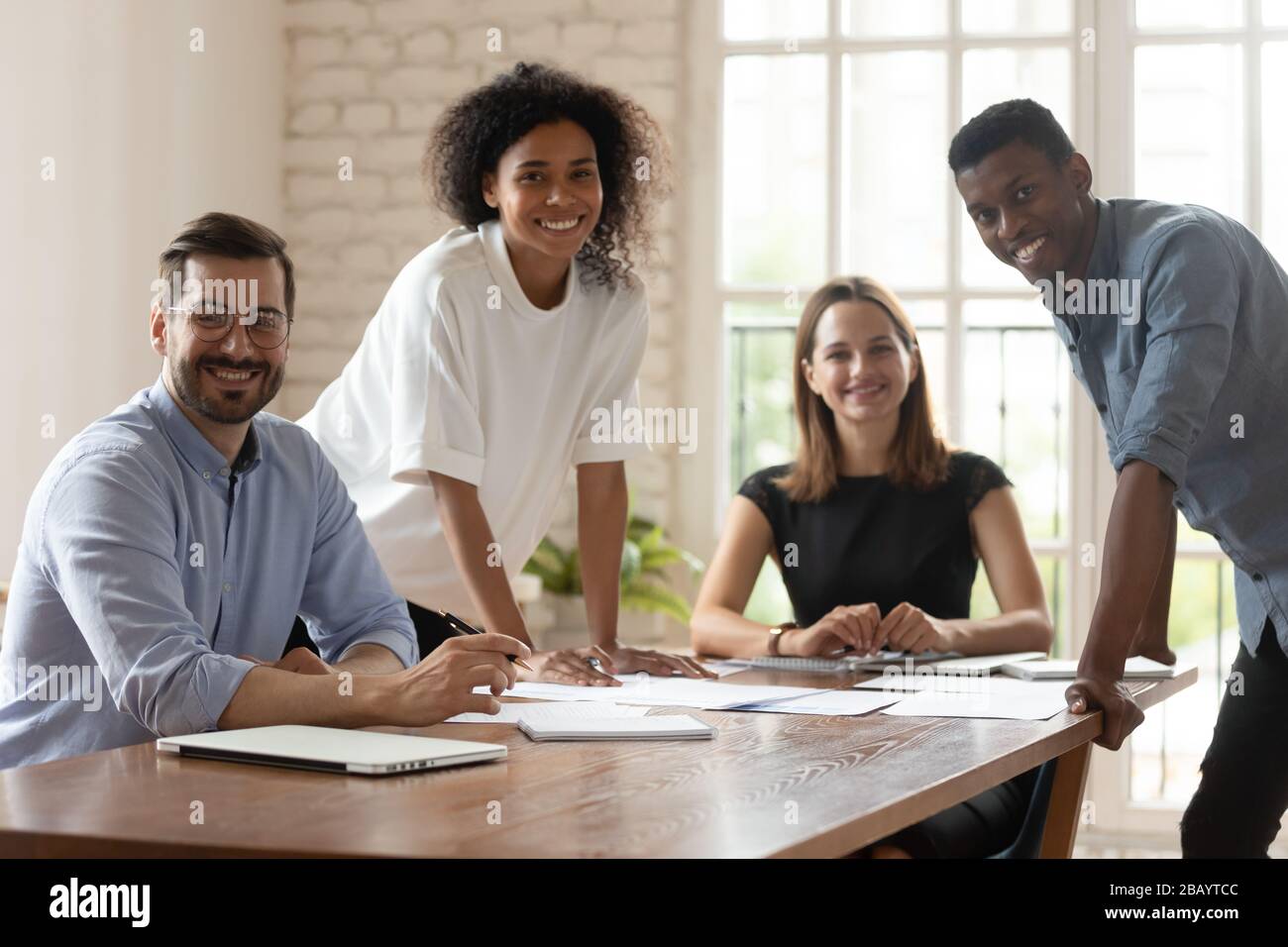 Fünf multiethnische Geschäftsleute versammeln sich im Sitzungssaal, lächelnd posiert sie für die Kamera Stockfoto