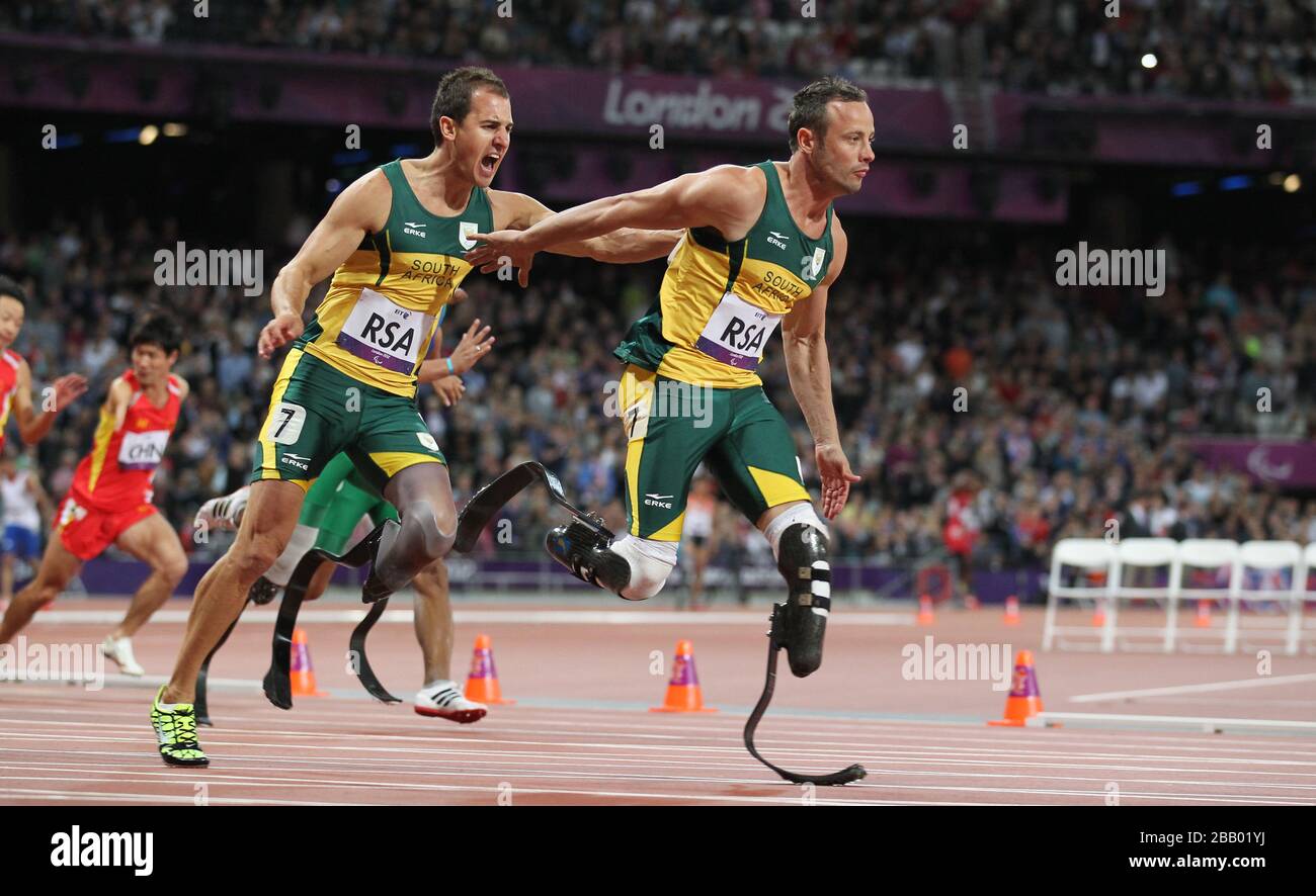 Der Südafrikaner Arnu Fourie übergibt Oscar Pistorius während der 4x100m - T42/T46 der Paralympischen Spiele 2012 in London im Olympiastadion London. Stockfoto