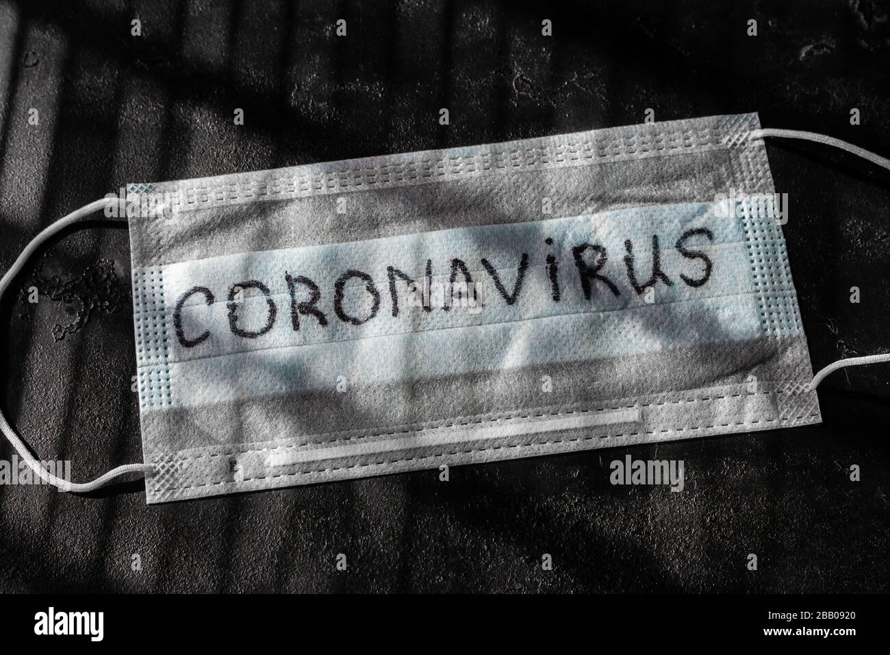 Medizinische Maske mit der Aufschrift Coronavirus in der Nähe auf schwarzem Hintergrund Stockfoto