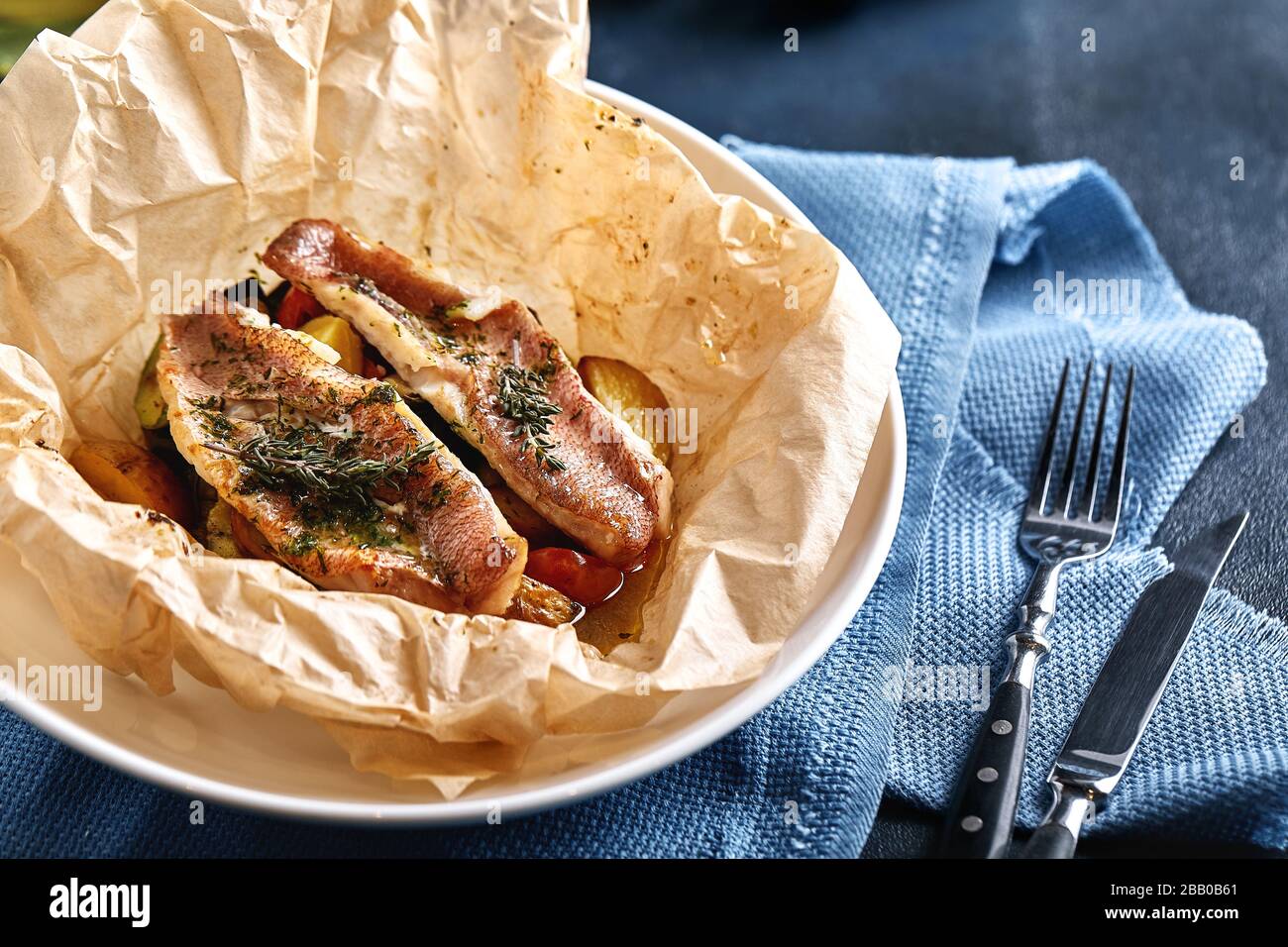Filet aus weißem Fischbestäuber, Kabeljau, Meerbarsch, Meerbrasse mit Oliven, Tomaten und Zitrone, in Pergament gebacken. Traditioneller italienischer Speisefisch papillo mit Stockfoto