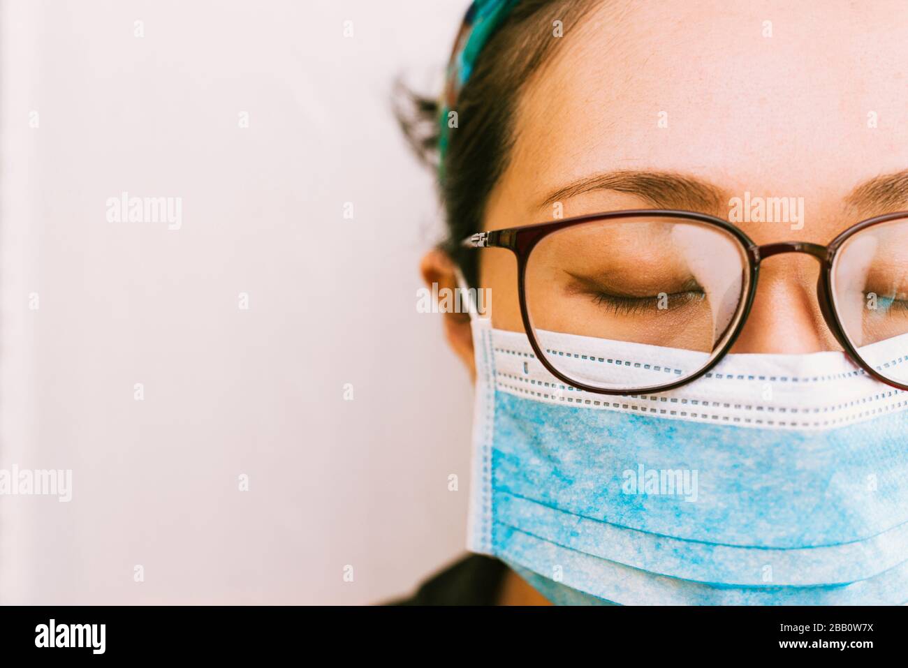 Coronavirus Thema. Asiatische Frau mit Brille, die eine Maske trägt, um sich vor Infizierung zu schützen Stockfoto