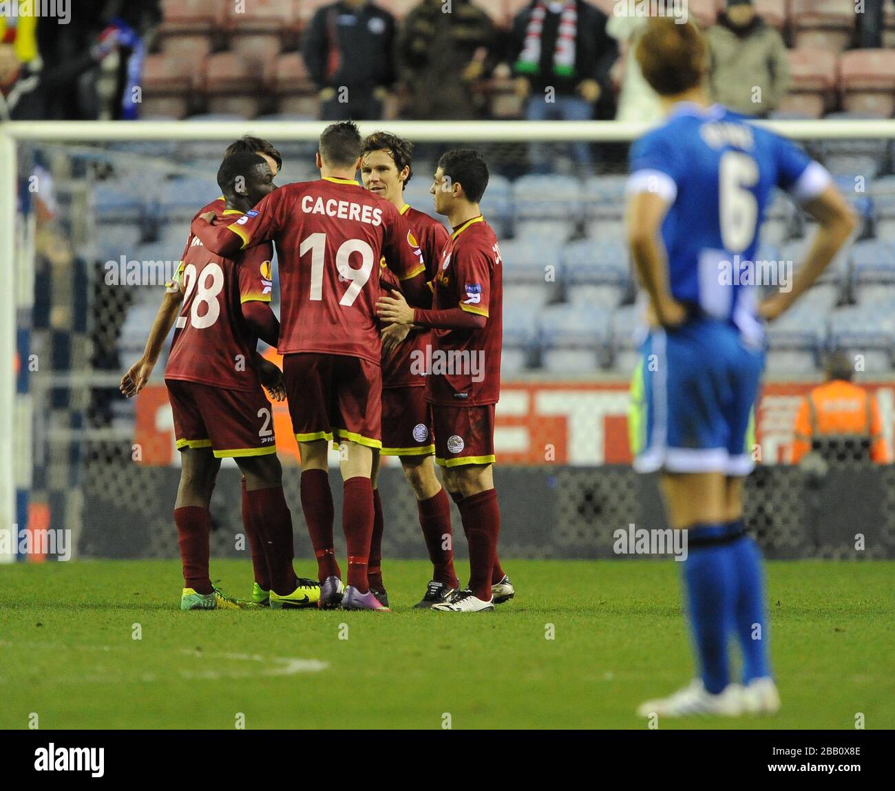 Die Spieler von Zulte-Waregem feiern nach dem Abpfiff, als Thomas Rogne (rechts) von Wigan Athletic niedergeschlagen steht. Stockfoto