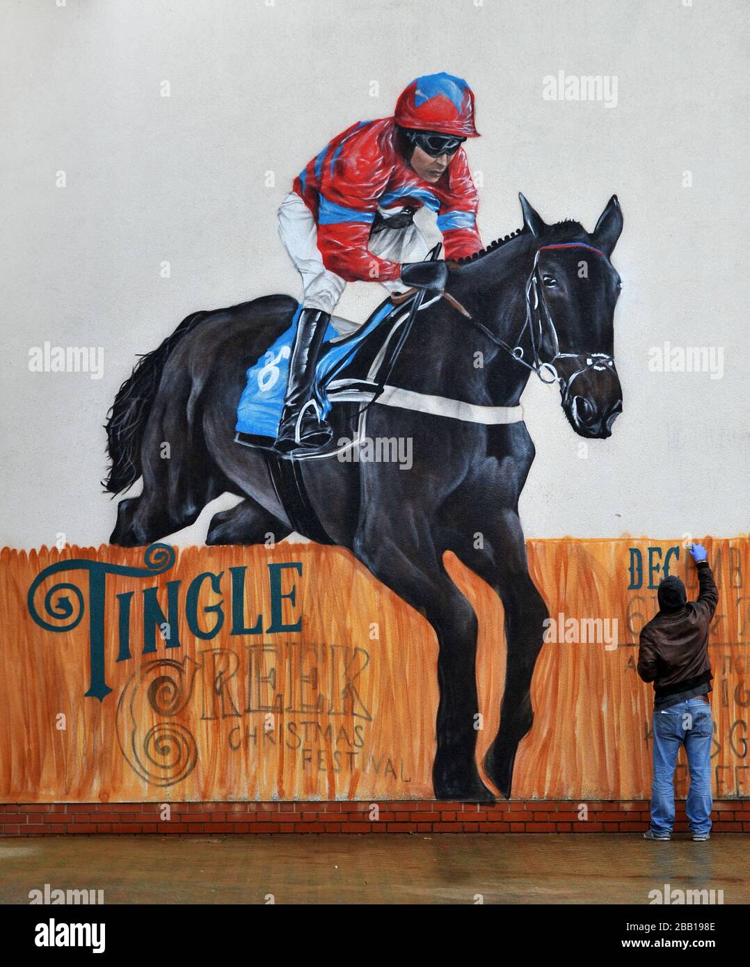 Der Graffiti-Künstler Olivier Roubieu wendet den letzten Schliff auf sein Wandbild an, das Sandown's Tingle Creek Christmas Festival während des Gentleman's Day wirbt Stockfoto