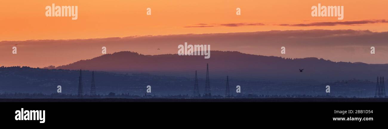 Blick auf die Hügel bei Sonnenuntergang in der South San Francisco Bay Area; im Vordergrund sind die Stromtürme und Stromleitungen zu sehen; Stockfoto