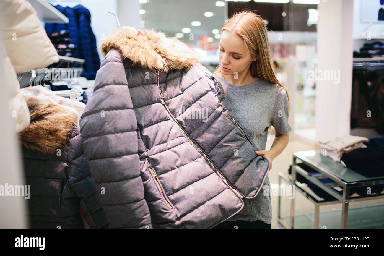 Schöne Blondine kauft neue Dinge in einem Bekleidungsgeschäft. Verkäufer arbeitet in der Boutique Stockfoto