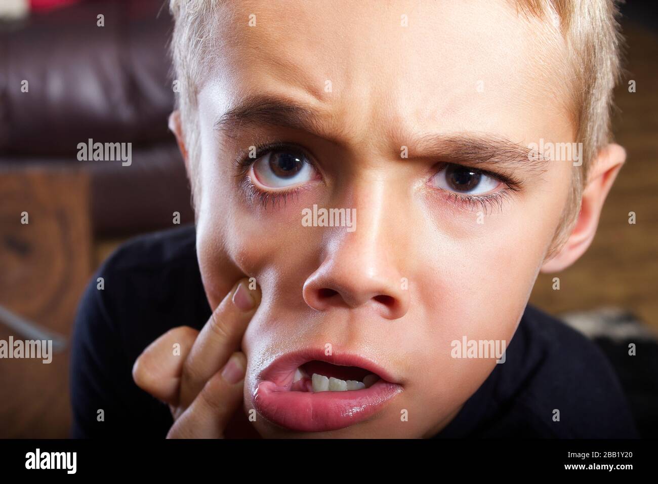 Ein Foto mit einem Kopfschuss aus der Nahaufnahme eines schönen jungen Jungen mit einem sehr lustigen Gesichtsausdruck und einfach albern. Er hat haselbraune Augen und blonde Haare. Stockfoto