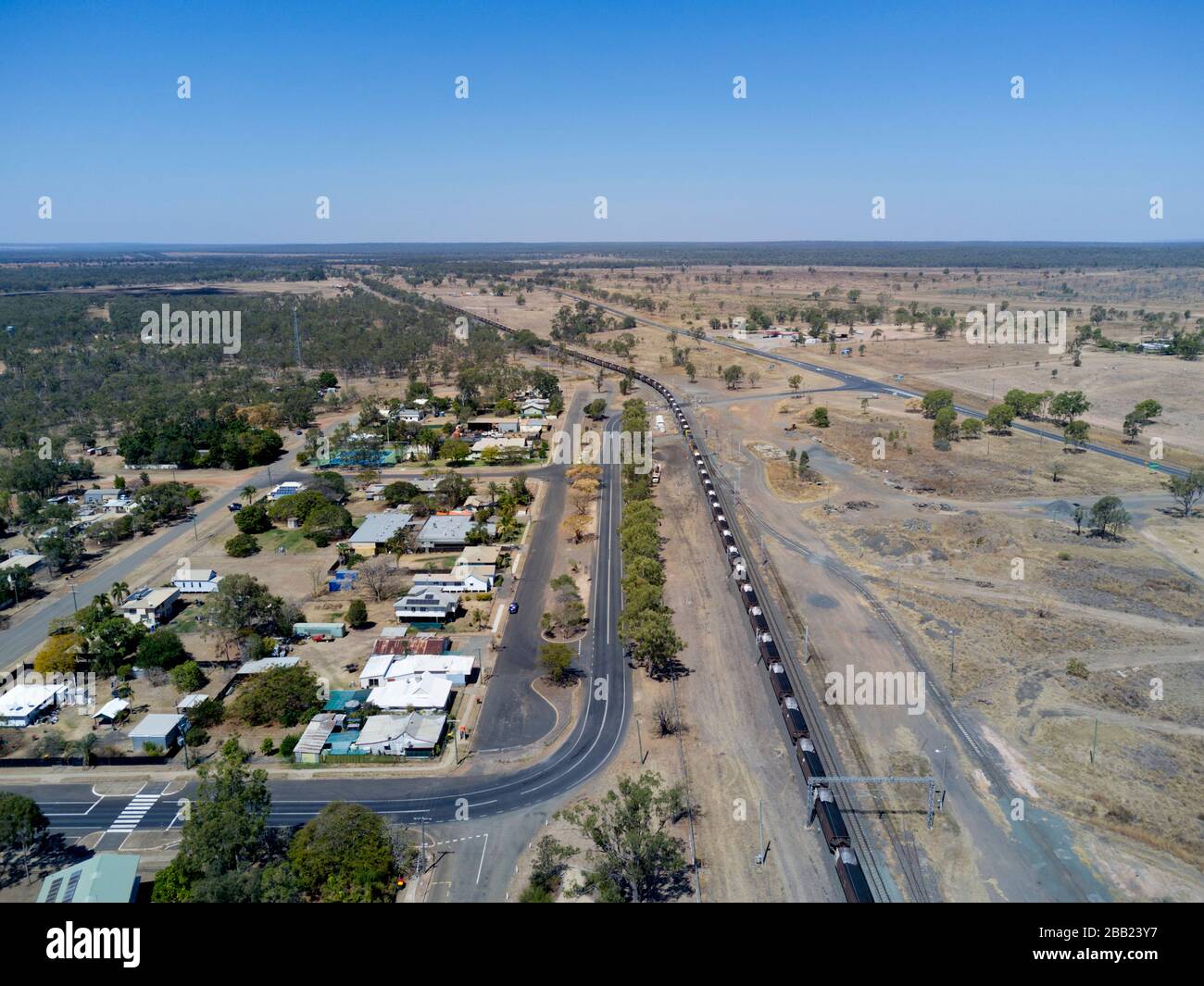 Antenne mit 120 Wagen und 2 km langem Güterzug, der den Export zum Hafen von Gladstone befördert, während er durch das Dorf Dingo Central Queensland führt Stockfoto