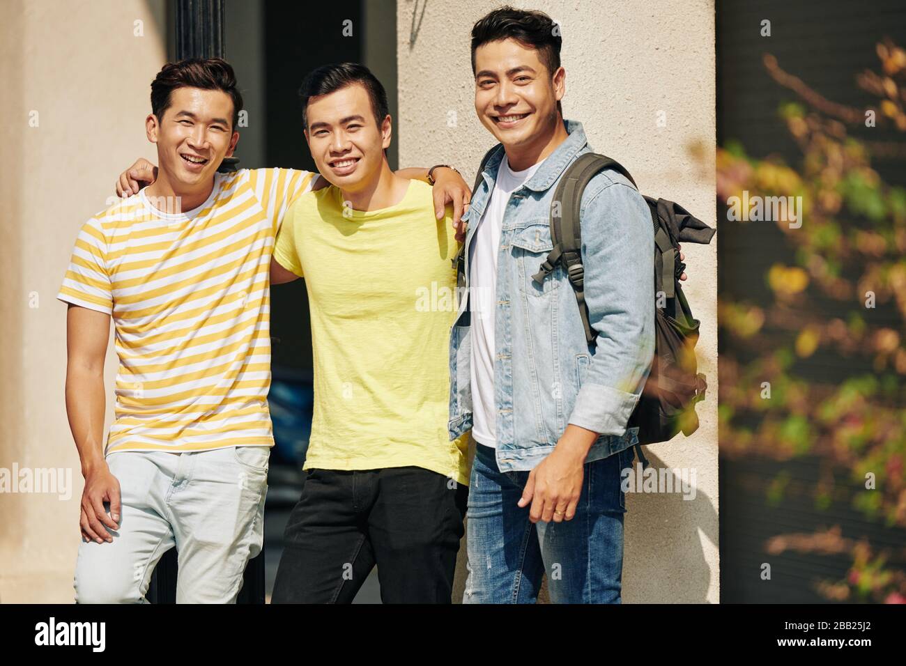 Eine Gruppe fröhlicher asiatischer Studenten, die die Kamera umarmen und lächeln Stockfoto