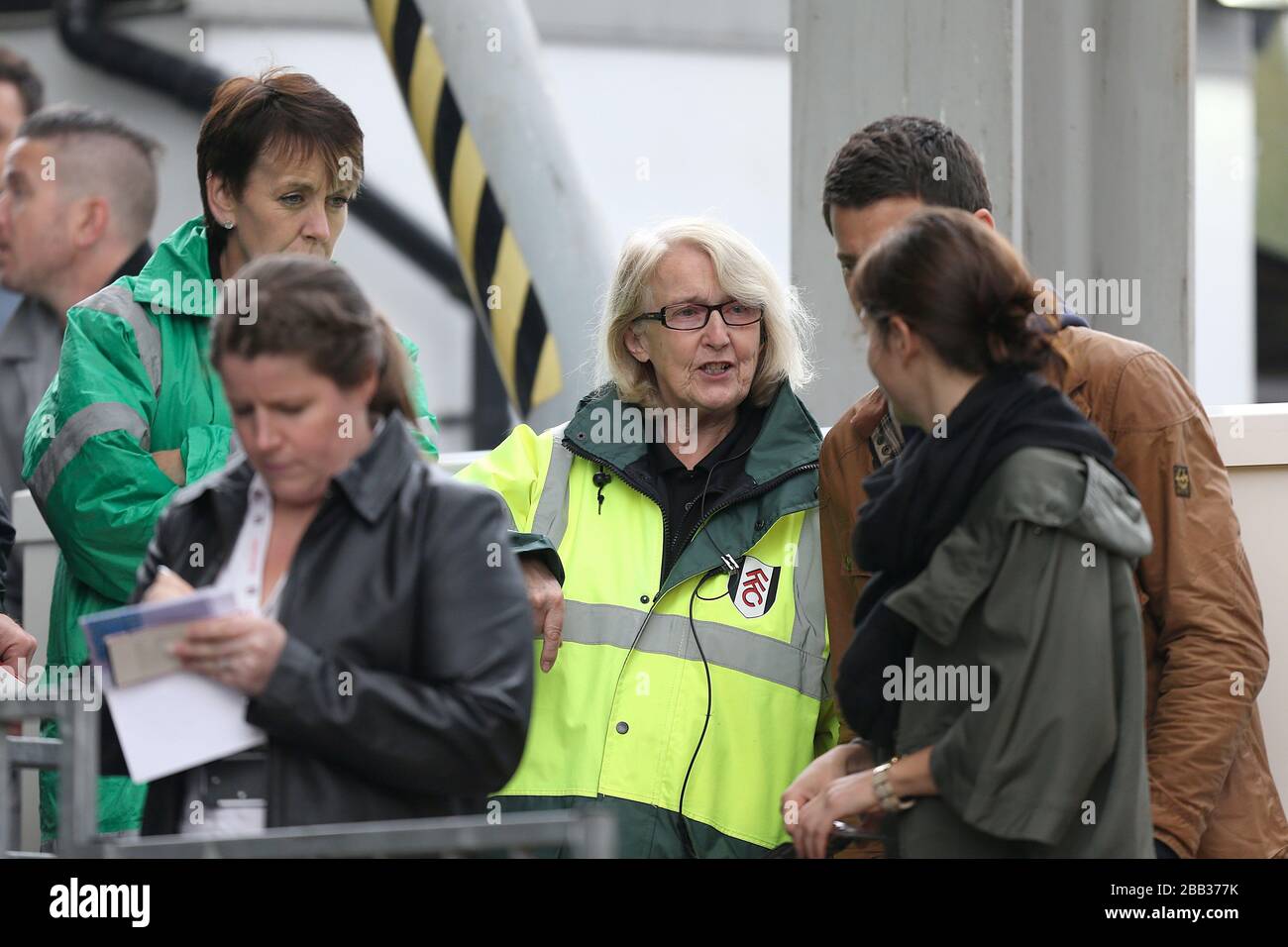 Ein Mitarbeiter von Fulham hilft Fans, vor dem Anpfiff ihren Platz zu finden Stockfoto