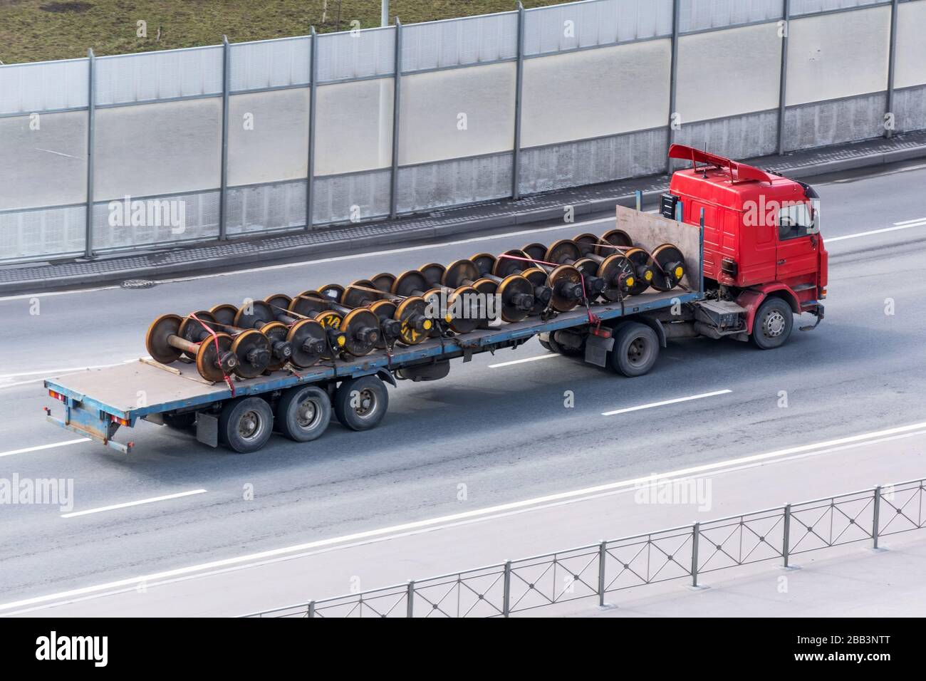 Güterkraftwagen mit offenem Anhänger, der auf der Autobahn fährt und mit  Radsätzen aus einem Zug von Waggons beladen ist Stockfotografie - Alamy