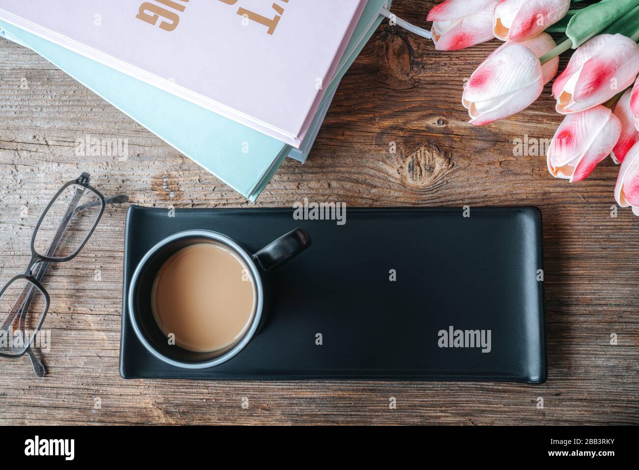 Kaffee in schwarzer Tasse mit Tablett und schöner Mockup-Dekoration auf Holztisch. Vogelperspektive, Mock-up-Konzept Stockfoto