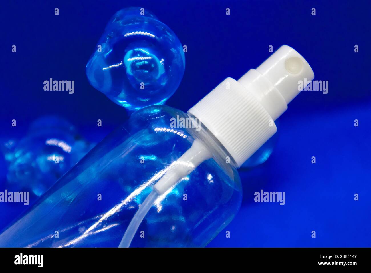 Sprühauslöser, weißer Kunststoffpulverisator auf blauem Hintergrund. Auslöser für Desinfektions-Spray-Kosmetik. Aerosol transparente Flasche Nahaufnahme. Reinigen Sie die Pflege Stockfoto