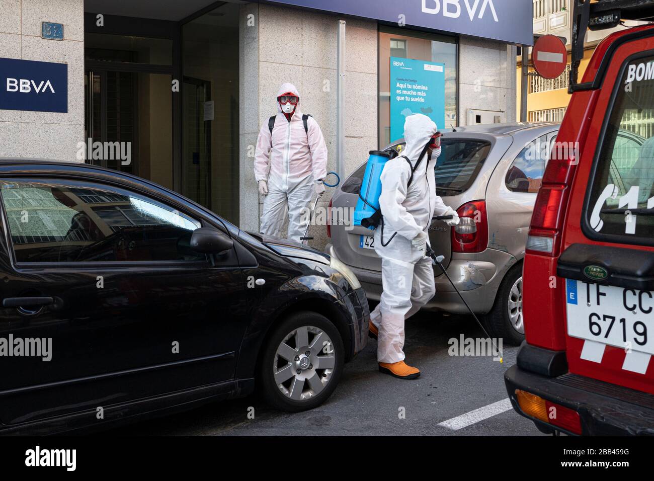 Freiwillige Feuerwehrleute in Schutzanzügen, die Desinfektionsmittel in Bereichen sprühen, in denen ein hoher Fußgängerverkehr herrscht, Playa San Juan, auf Tenera-Gebiet Stockfoto