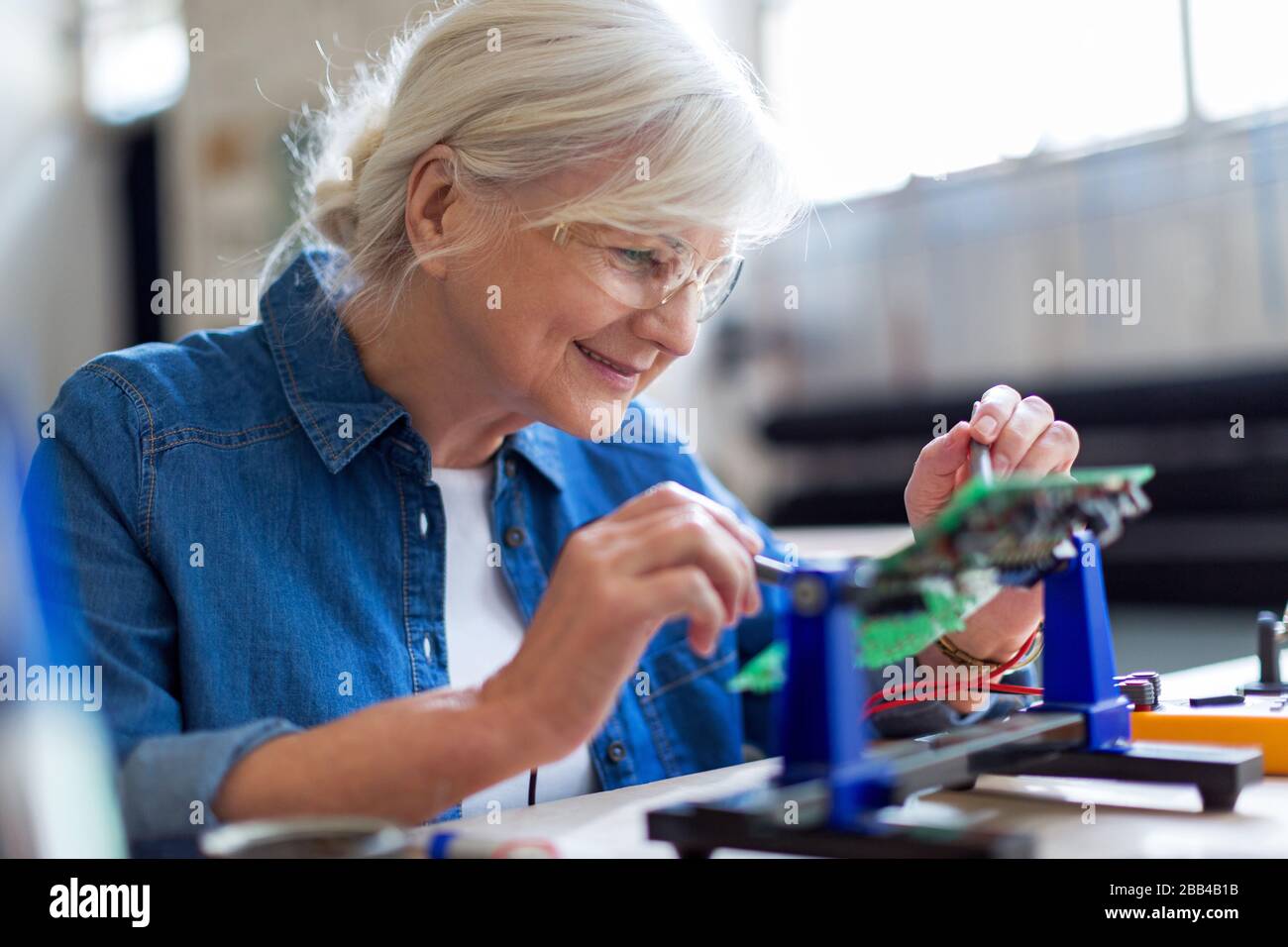 Seniorin in der Elektronikwerkstatt Stockfoto