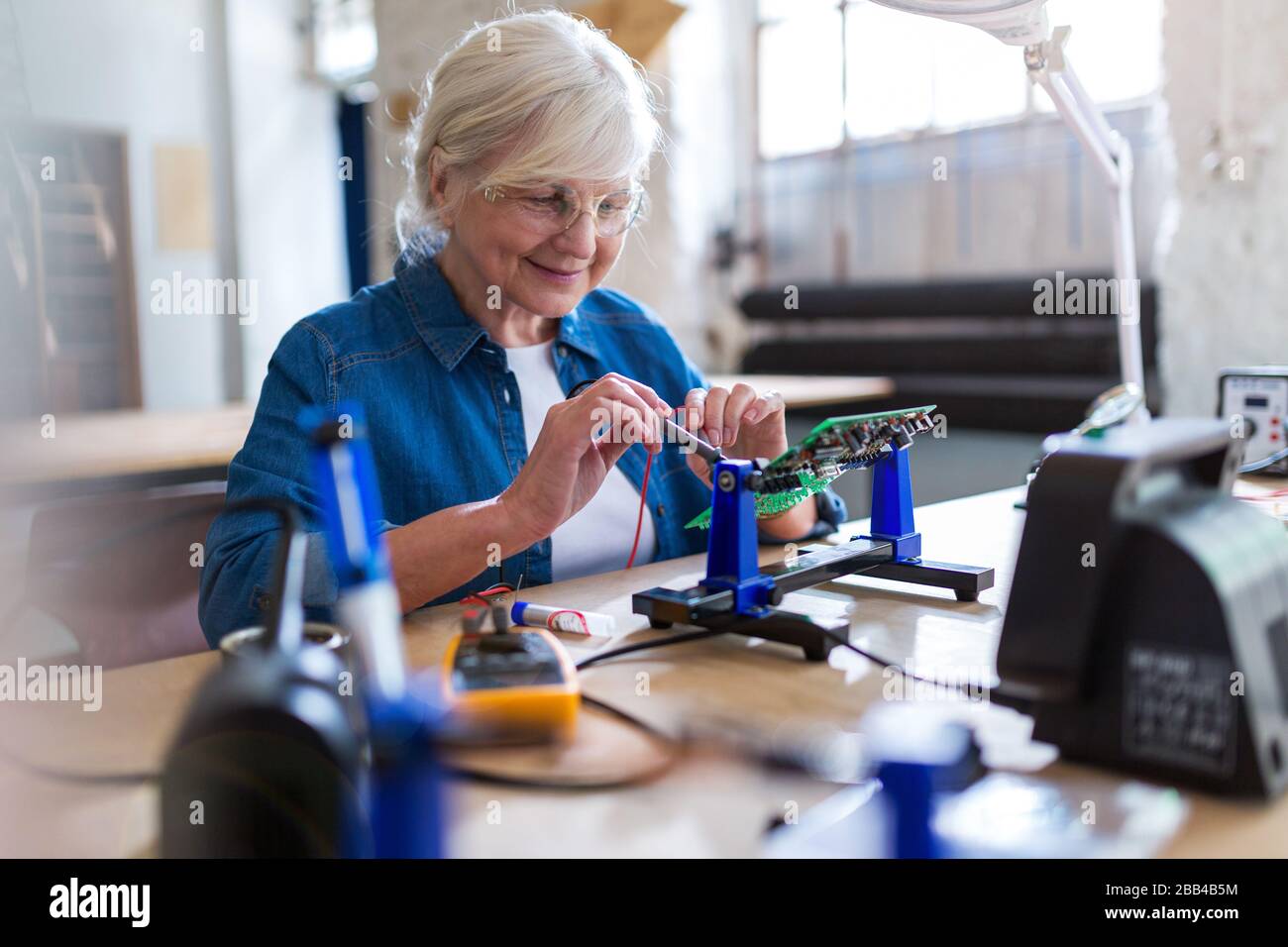 Seniorin in der Elektronikwerkstatt Stockfoto